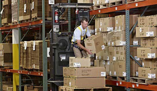 man unloads product from warehouse shelf onto pallet using rental forklift
