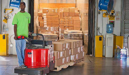 Worker uses rental pallet jack for material handling in warehouse setting