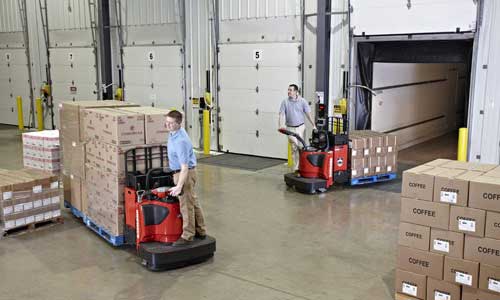 Two warehouse employees transport goods with used lift trucks